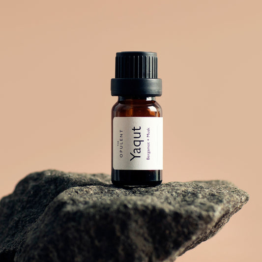 Small brown bottle with a label on a textured rock against a beige background